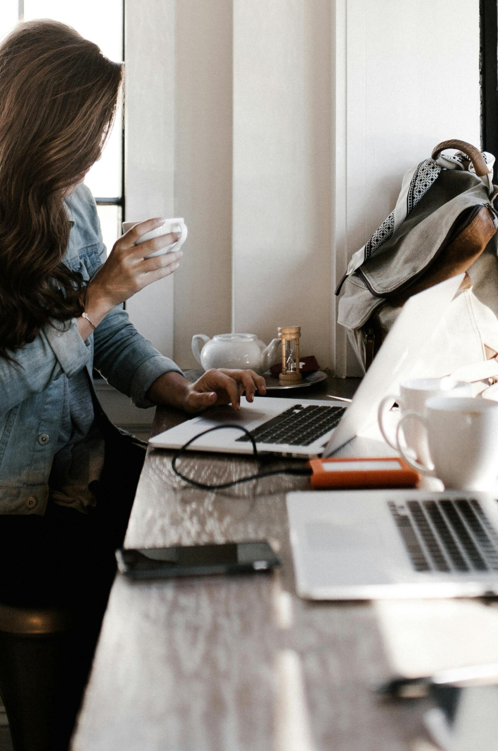 a woman working on a laptop and drinking tea